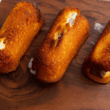 Golden, crispy air fryer Twinkies served on a plate with powdered sugar.
