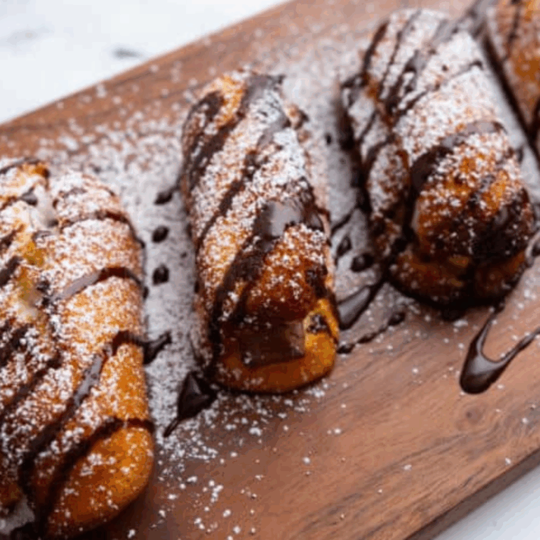 Air fryer Twinkies with golden crust, topped with powdered sugar and chocolate drizzle.