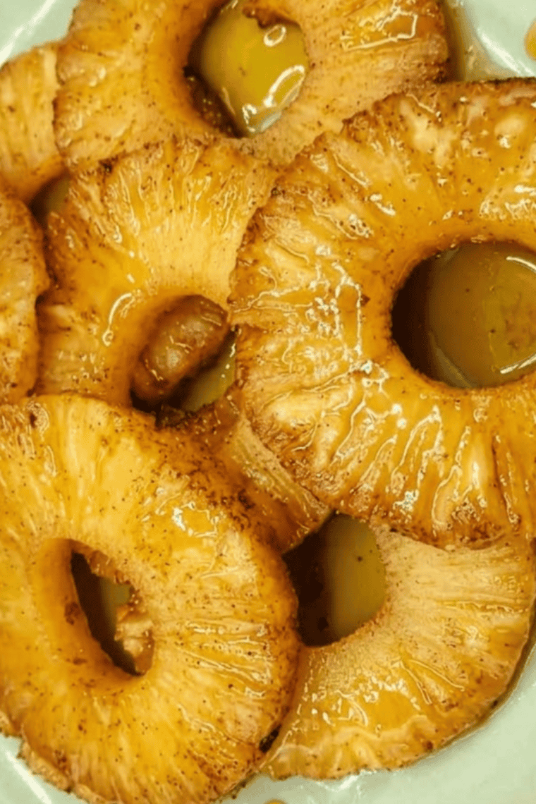Pineapple rings in air fryer basket cooking until caramelized and golden brown.
