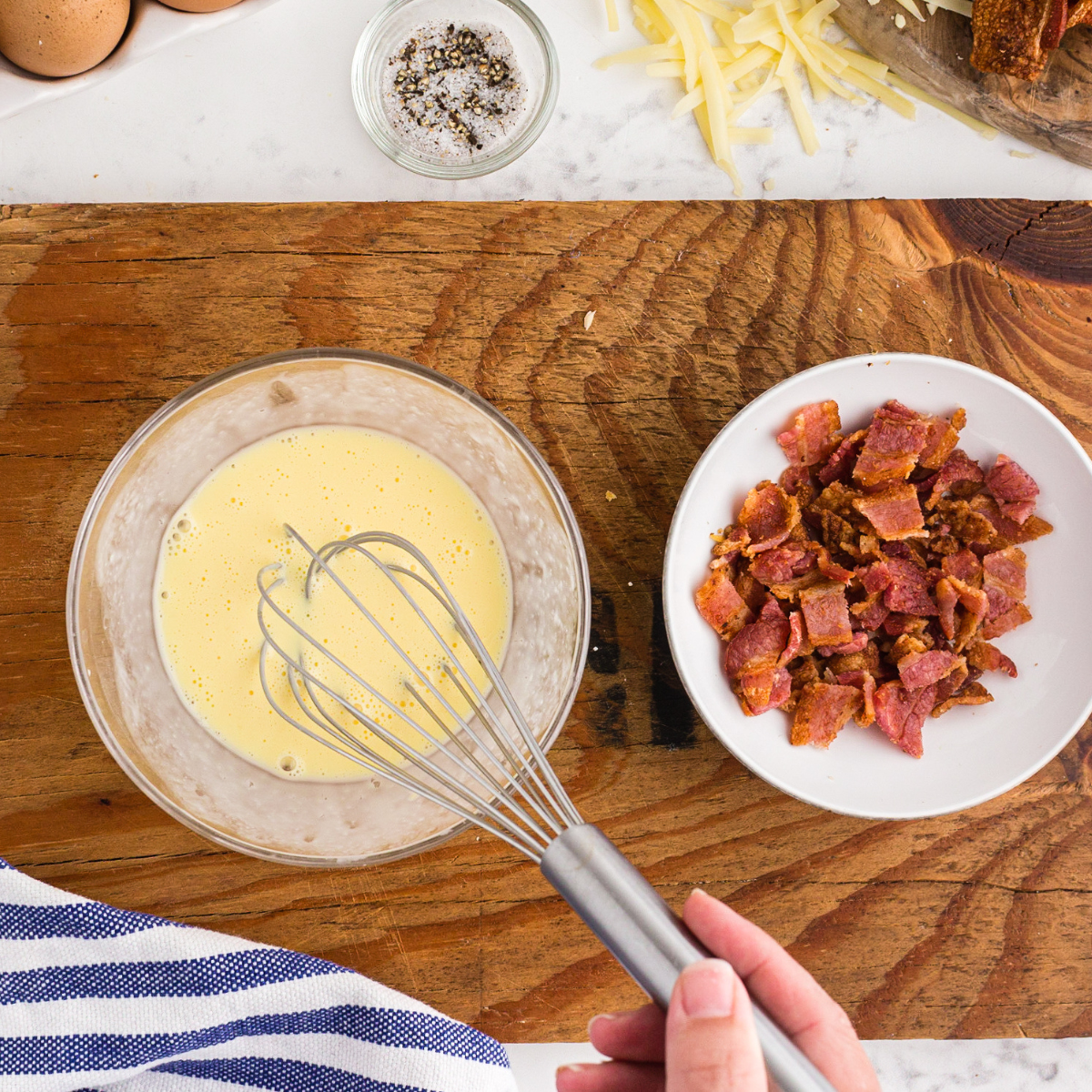 Preparing the filling for copycat La Madeleine Quiche Lorraine in a small mixing bowl.