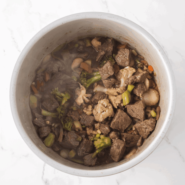 Cooking beef and vegetables in Ninja Foodi, stirring frequently until beef is fully cooked.