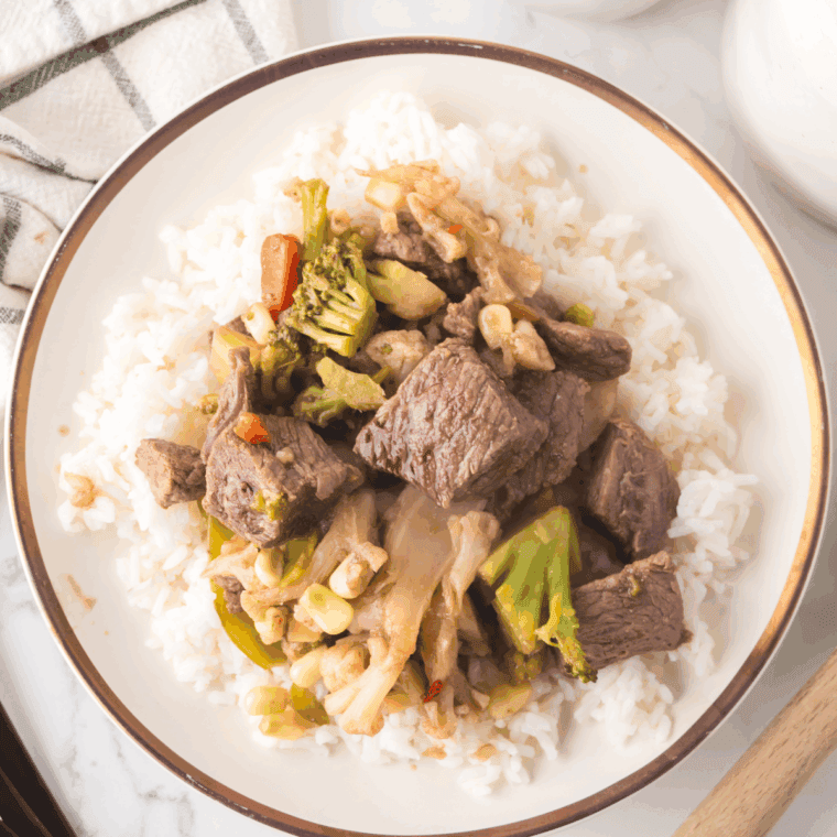 Pouring sauce over beef and vegetables in Ninja Foodi, tossing to coat and cooking until sauce thickens, ready to serve.