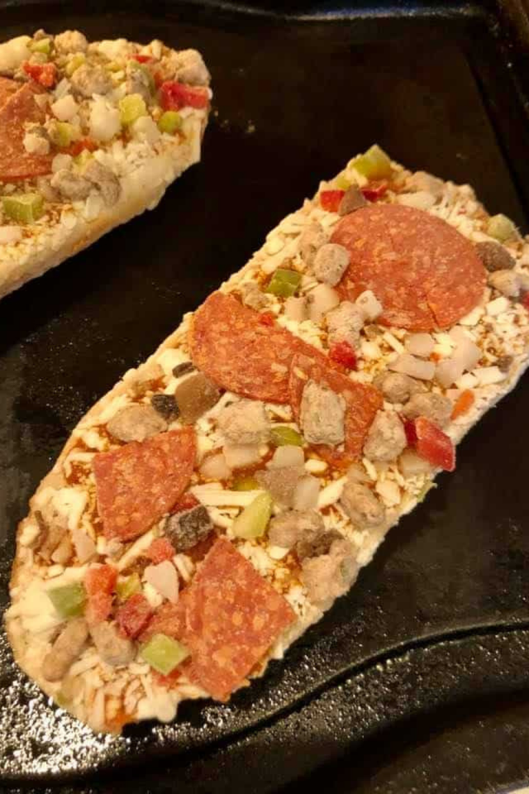 Frozen French bread pizza arranged in air fryer basket in single layer