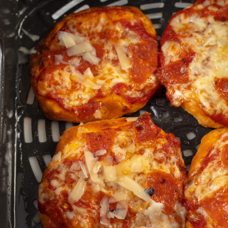 Air fryer biscuit pizzas in the basket, cheese fully melted and crusts golden brown