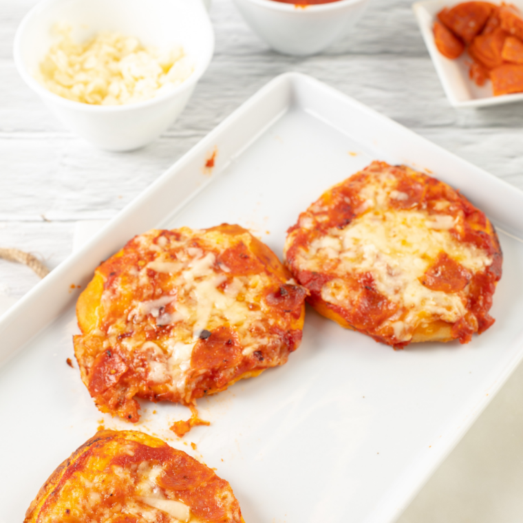 Four air fryer biscuit pizzas arranged on a white plate
