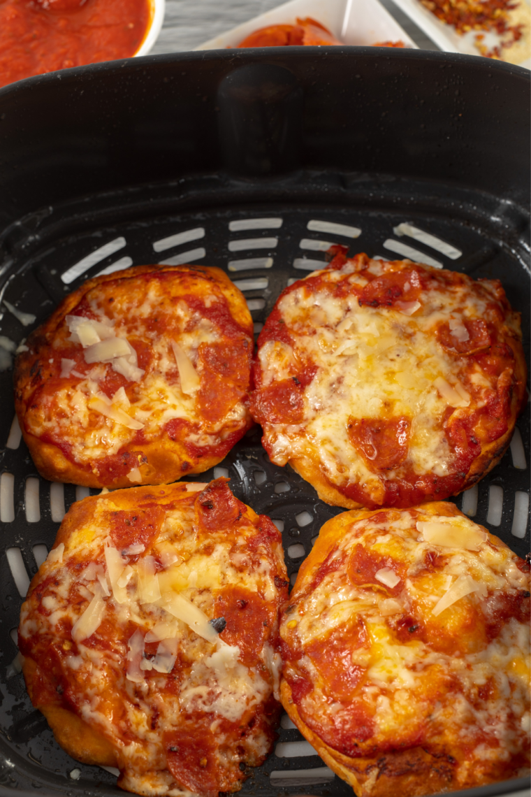 Finished pepperoni biscuit pizzas in an air fryer basket, hot and ready to serve