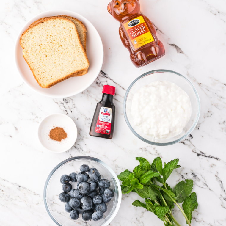 Ingredients needed for Air Fryer Blueberry Honey Ricotta Toast on kitchen table, marble.