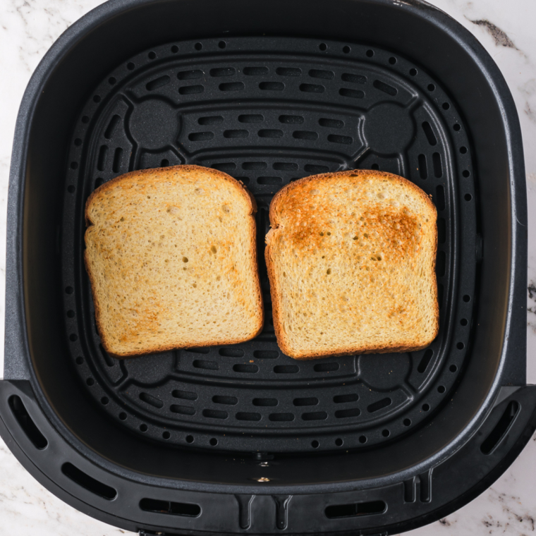 Toasted bread in the air fryer basket, getting ready for the toppings.