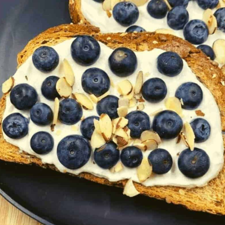 Beautifully arranged Air Fryer Blueberry Honey Ricotta Toast with a side of fresh blueberries.