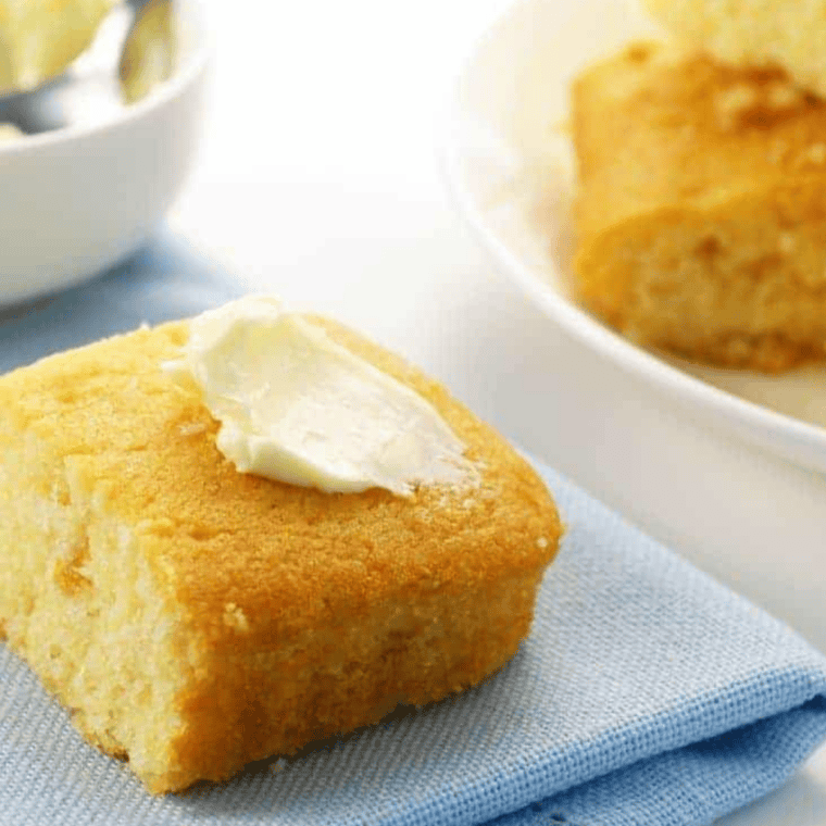 Golden slice of creamed corn cornbread baked in the air fryer, served on a plate with a pat of melting butter.