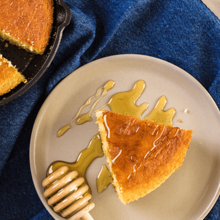 Slice of air fryer creamed corn cornbread with golden edges, served with butter on a rustic plate.