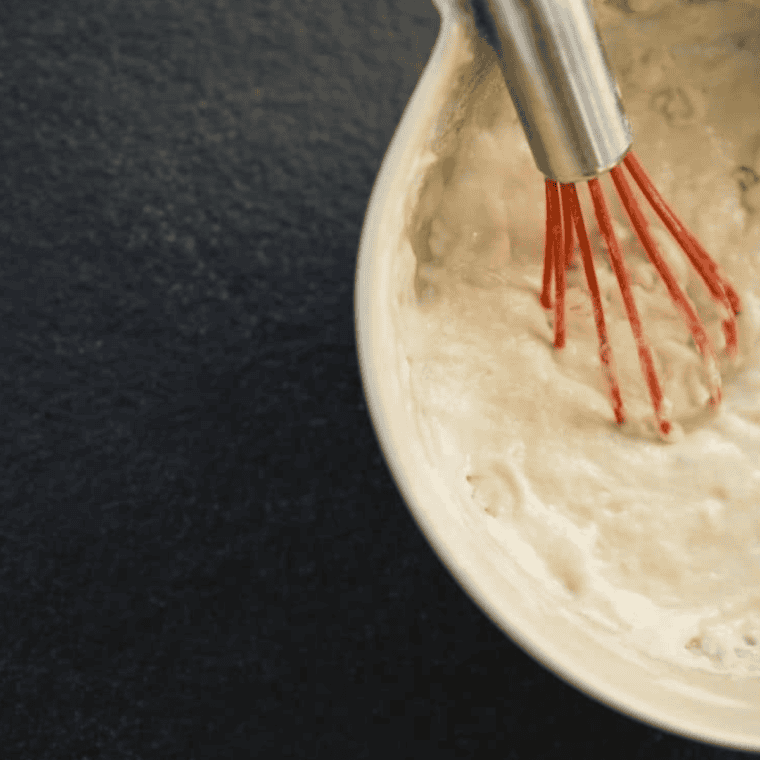 Mixing cornmeal, flour, sugar, baking powder, and salt with creamed corn, milk, and egg in a large bowl.