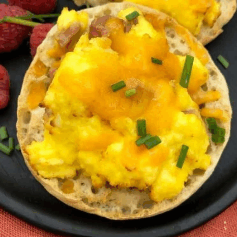 A freshly made Air Fryer English Muffin Breakfast Pizza, topped with melted cheese, egg, and savory toppings.