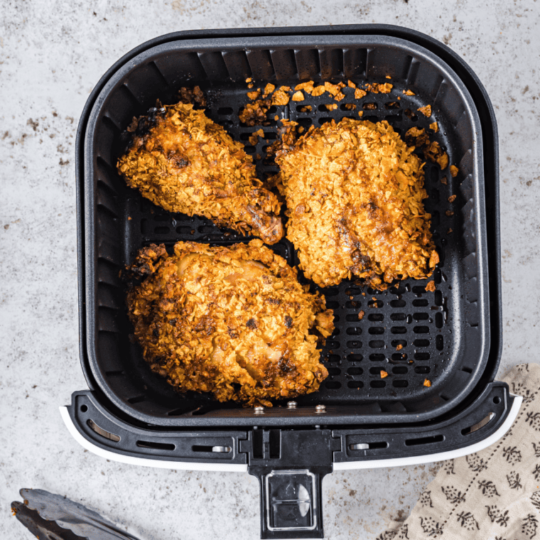 Coated chicken breasts arranged in a single layer in the air fryer basket