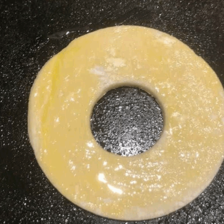 Brushing puff pastry donuts with beaten egg for a golden finish.