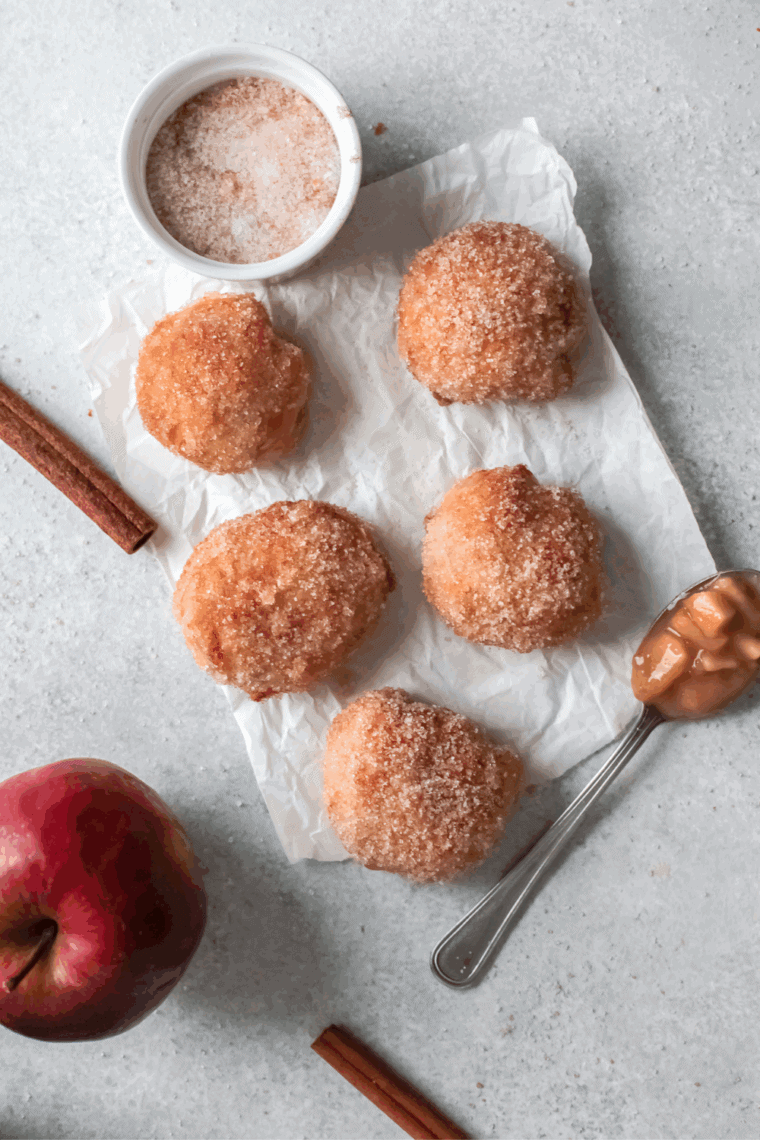 Homemade Dunkin’ Donut Munchkins coated in cinnamon sugar and powdered sugar, stacked on a serving plate.