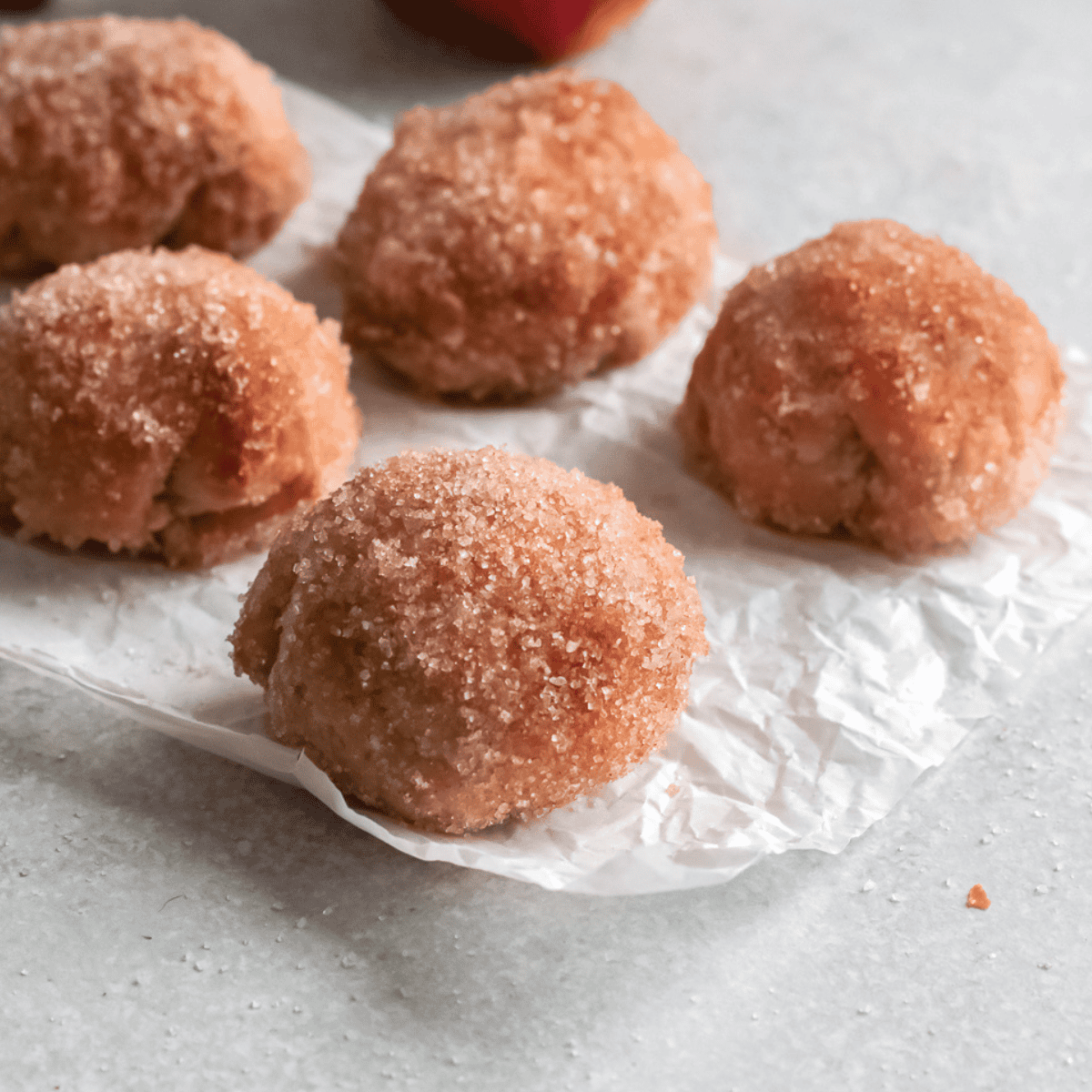 Plate of golden, homemade Dunkin' Donut Munchkins dusted with powdered sugar and ready to serve.