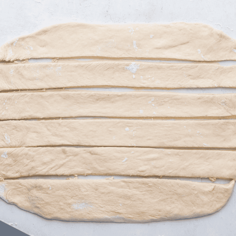 Dough strips rolled into ropes and tied into knots, placed on a plate ready for air frying.