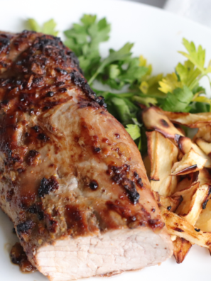 A succulent Air Fryer BBQ Pork Tenderloin glazed with barbecue sauce, sliced and served on a platter, garnished with fresh herbs.