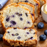 Sliced air fryer blueberry bread on a wooden board showing blueberries in the crumb