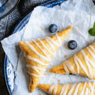 Golden, flaky blueberry turnovers cooked in the air fryer, served on a plate.