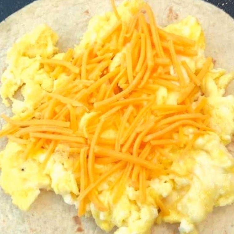 Place tortilla in air fryer, add scrambled eggs, cheese, and another tortilla on top.