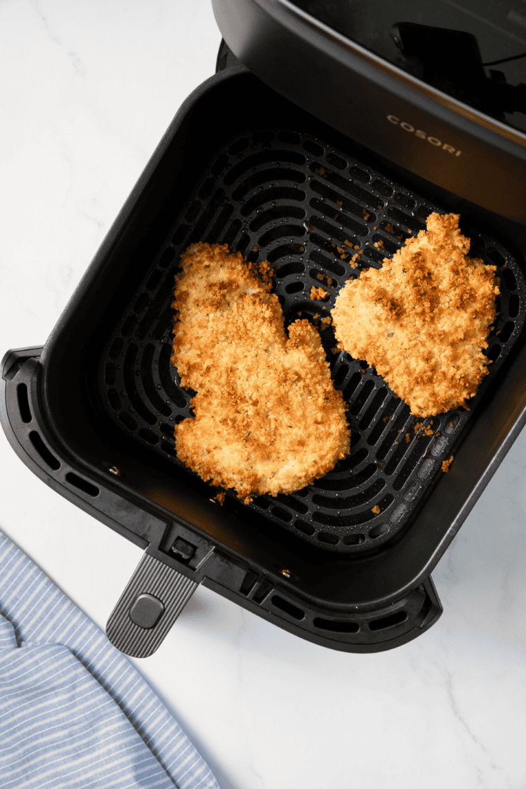 Haddock fillets arranged in a single layer in the air fryer basket.