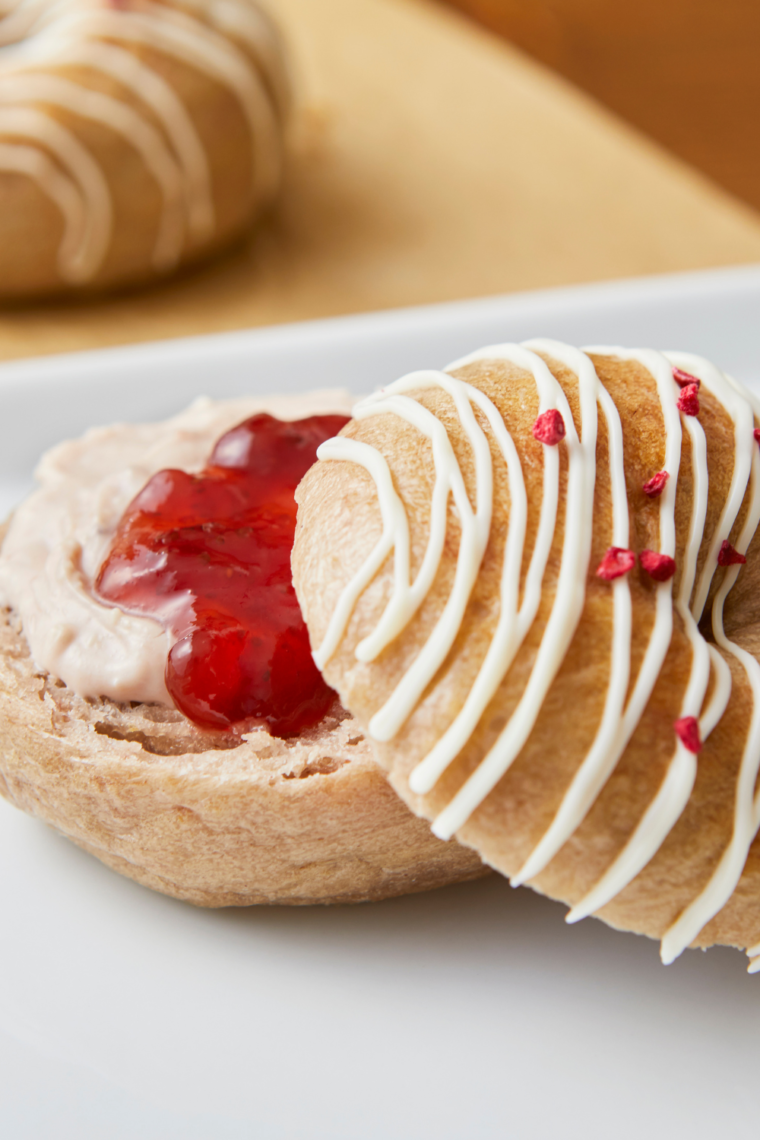 Strawberry bagel on a white plate with cream cheese and strawberry jam spread on top