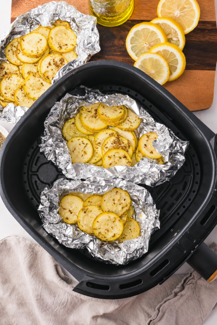 Sliced summer squash tossed with seasoning arranged in a single layer in an air fryer basket