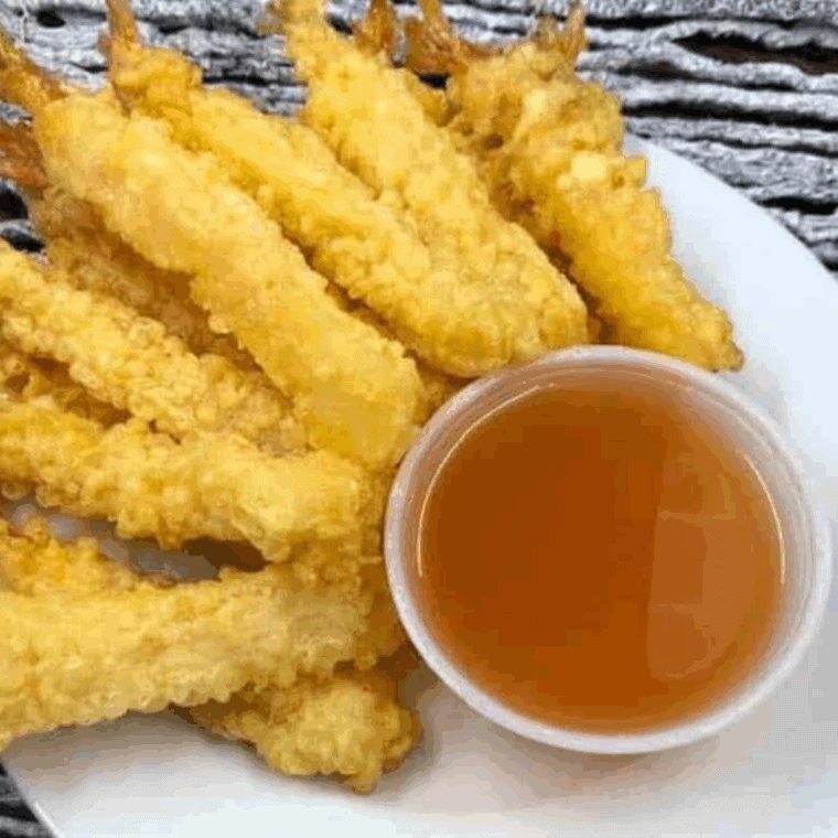 Crispy golden tempura shrimp on a plate, served with dipping sauce, inspired by Benihana restaurant.