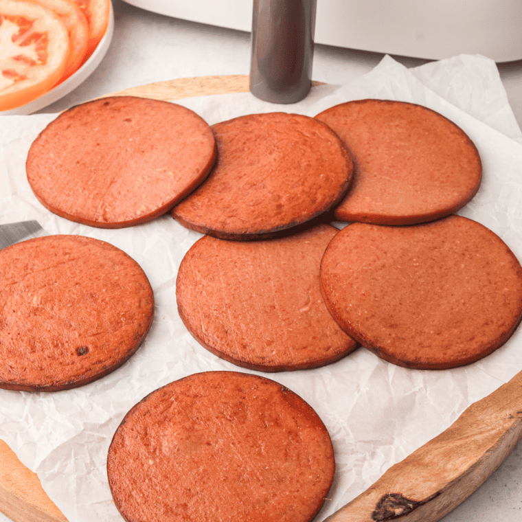 Crispy, golden fried bologna slices fresh out of an air fryer basket.