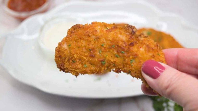 closeup: a woman's hand holding a dorito chicken tender