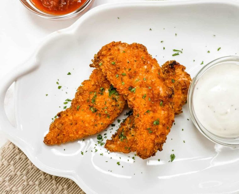 overhead: doritos chicken strips on a white plate with white dipping sauce