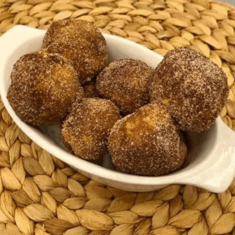 Close-up of golden biscuit donut holes made in the air fryer, coated with cinnamon sugar.