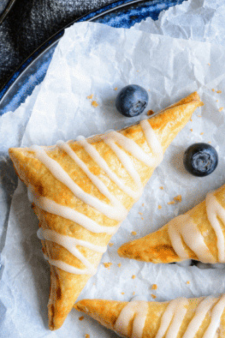 Golden air fryer blueberry turnovers on a plate, crispy pastry with juicy blueberry filling.