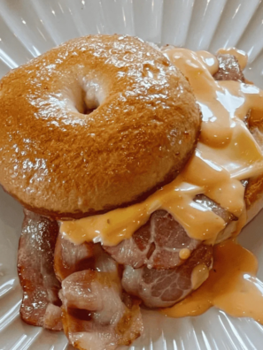 Air Fryer Cheddar Cheese Bagels stacked on a wooden board with golden melted cheddar on top and a crispy golden-brown crust.