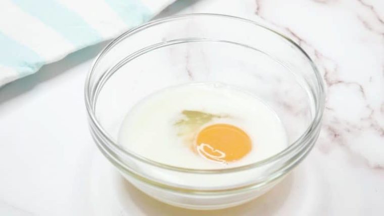 a glass bowl with milk and egg