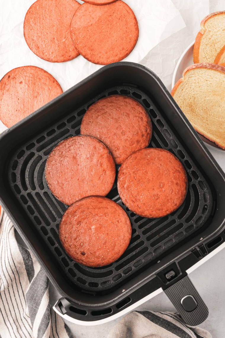 Crispy air fryer fried bologna slices stacked on a plate, ready to enjoy.