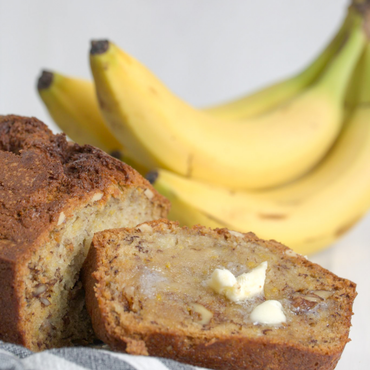 Close-up of moist air fryer banana nut bread sliced on a wooden board with visible banana chunks and chopped walnuts inside.