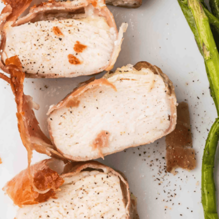 Crispy air-fried chicken saltimbocca with prosciutto and sage, served with lemon wedges on a white plate