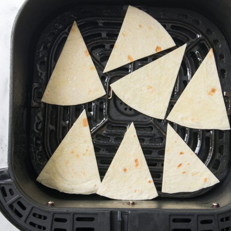 "Cutting corn tortillas into triangles to create nacho chips."