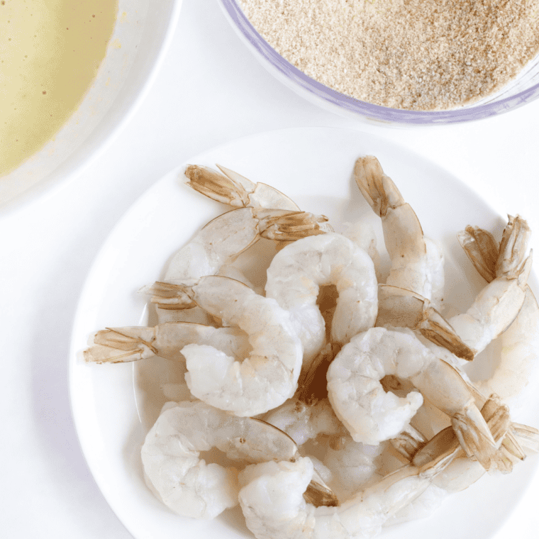 Peeled and deveined raw shrimp being patted dry with paper towels.
