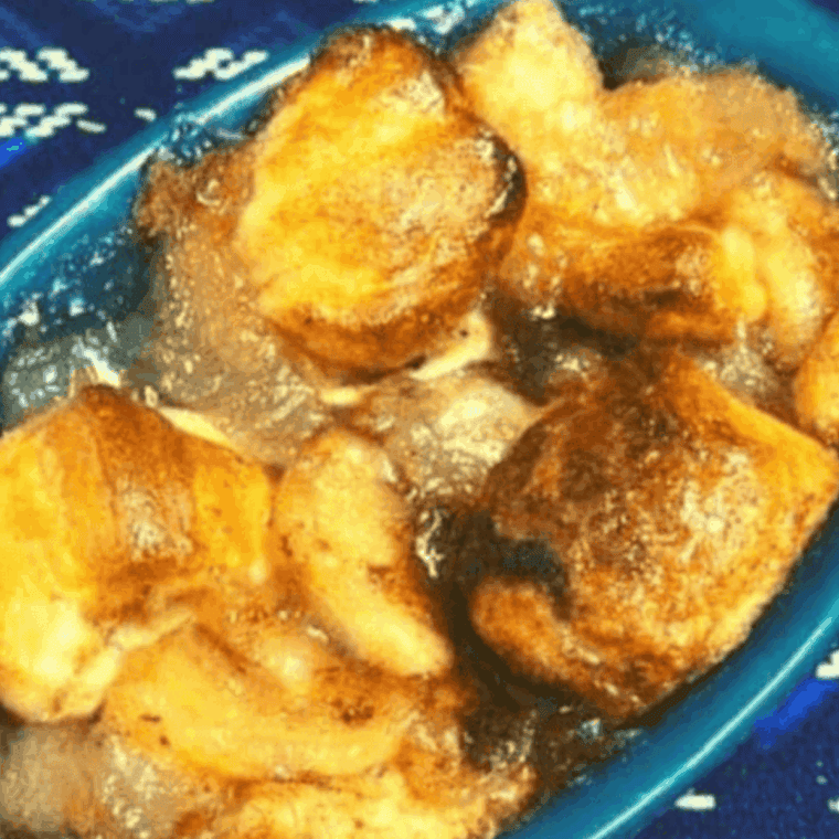 Warm apple pie biscuit casserole with golden biscuits and cinnamon-spiced apples, drizzled with glaze, served in a baking dish.