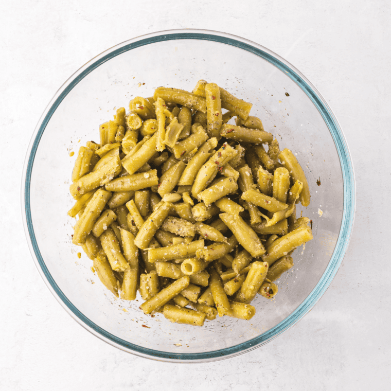 Toss canned green beans with olive oil and seasonings, including garlic powder, onion powder, salt, pepper, Parmesan, and red pepper flakes.