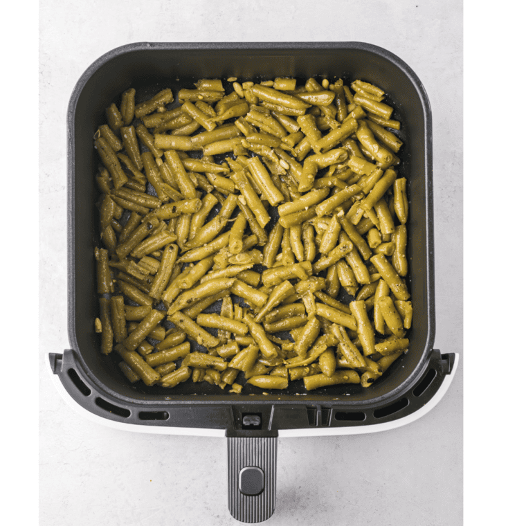 Preheat air fryer to 380°F, spread seasoned green beans in a single layer, and cook for 5-7 minutes, shaking halfway through.