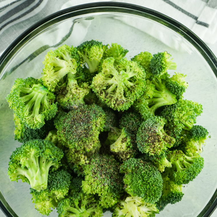 Seasoning the broccoli with the olive oil and seasonings in a large mixing bowl.