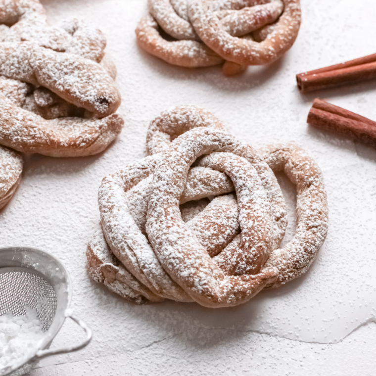 Close-up of warm funnel cake sprinkled with powdered sugar on a serving plate