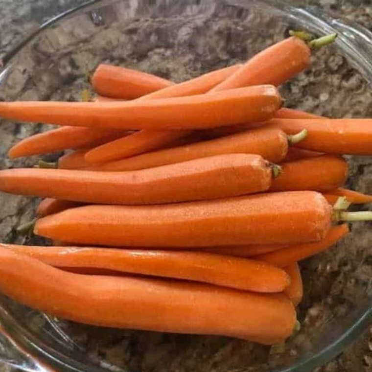 Peeled carrots on countertop in a glass bowl.