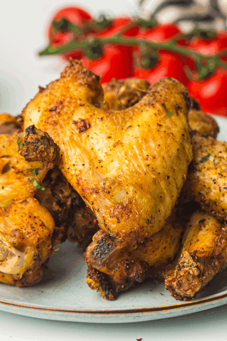 Crispy air fryer chicken wings coated in a golden honey mustard glaze, served on a white plate with parsley garnish.