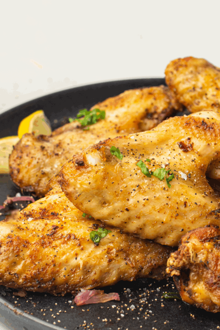 Golden-brown air fryer chicken wings coated in honey mustard sauce, served on a plate with parsley garnish.